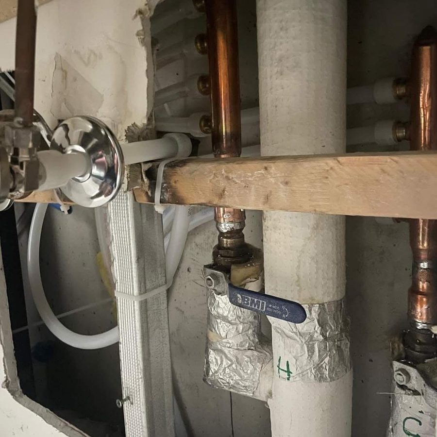 Copper and PEX rough-in work at a manifold behind an open wall