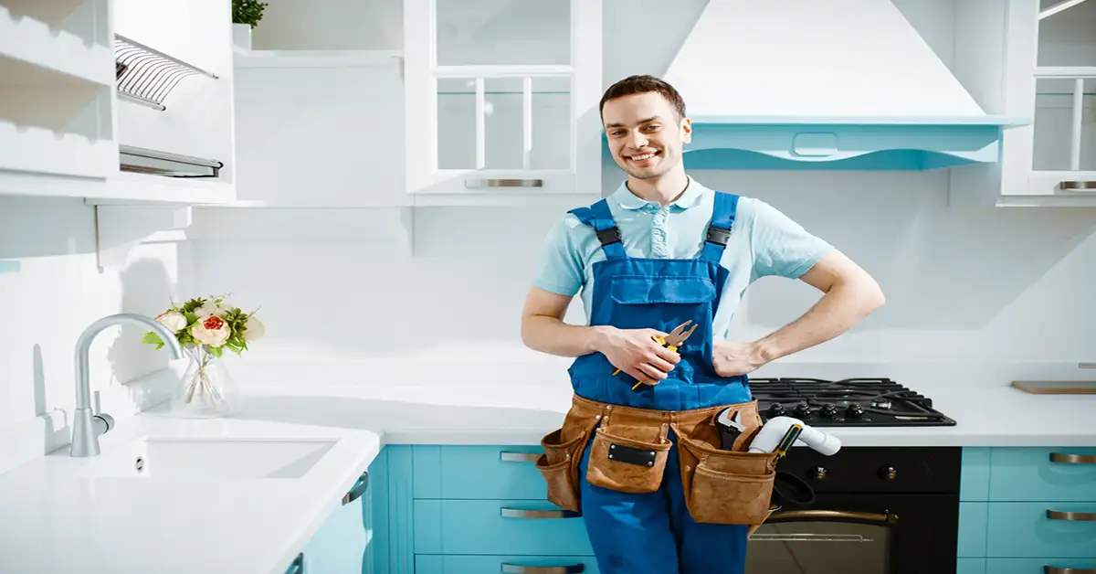 cheerful male plumber- uniform poses kitchen